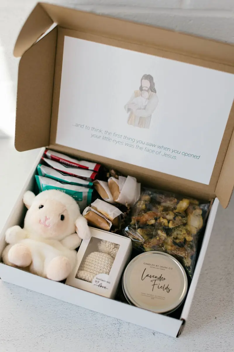 Warmth & Softness — A crocheted hat (cream, blue, or pink), a candle in a tin, caramels & pretzels, warm drink packets, and a soft stuffed lamb.