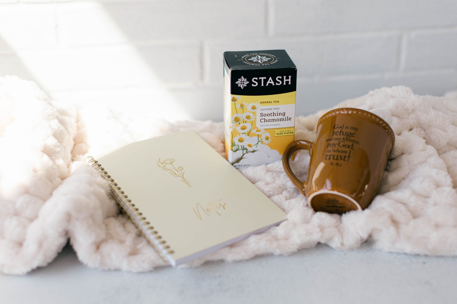 Rest & Reflection — A throw blanket, a mug, a box of tea, and a journal.