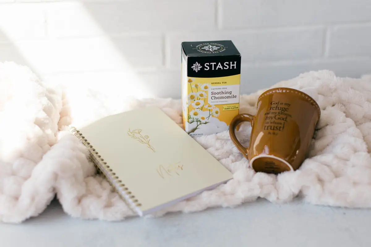 Rest & Reflection — A throw blanket, a mug, a box of tea, and a journal.